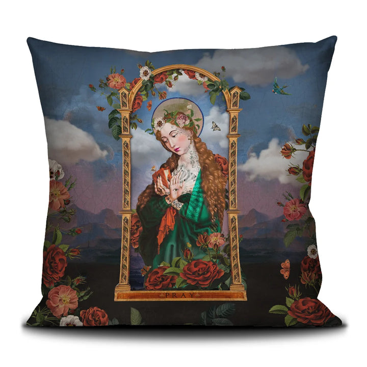 Voglio Bene Pray-tyynyn etunäkymä, jossa punahiuksinen nainen vihreässä kaavussa kultaisten kehysten ympäroimänä pitelee kirjaa kädessään ja toisessa kämmenessä on silmäsymboli. Taustalla pilvinen vuorimaisema ja kukkia.
Front view of Voglio Bene Pray -cushion featuring a red-haired woman in a green robe inside golden frames holding a book in one hand and an eye symbol in the palm of the other. The background depicts a cloudy mountain landscape with flowers.