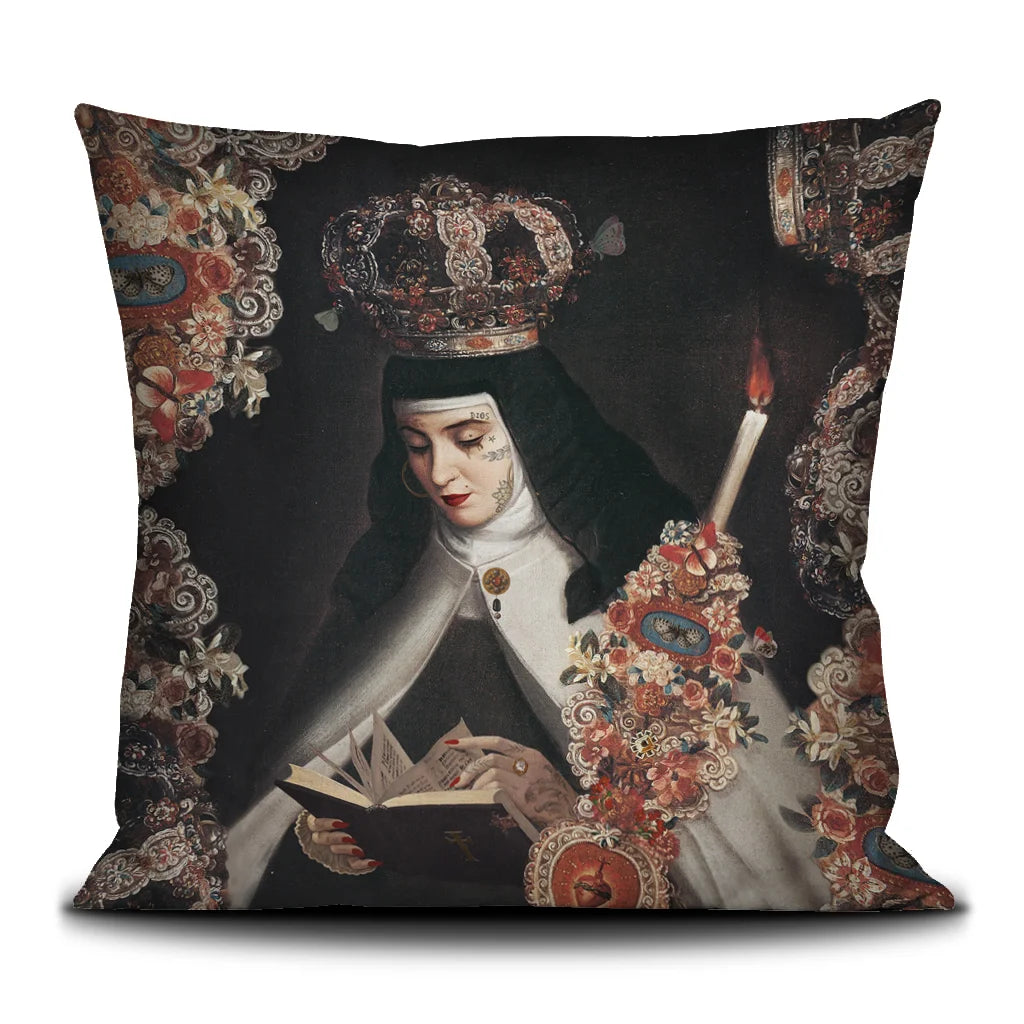 Voglio Bene Prayer -tyynyn etunäkymä. Kuvassa tatuoitu nunna kruunu päässään lukee kirjaa kukkien ja kynttilän reunustamana.
Front view of a Voglio Bene Prayer cushion. The illustration shows a tattooed nun wearing a crown, reading a book framed by flowers and a candle.