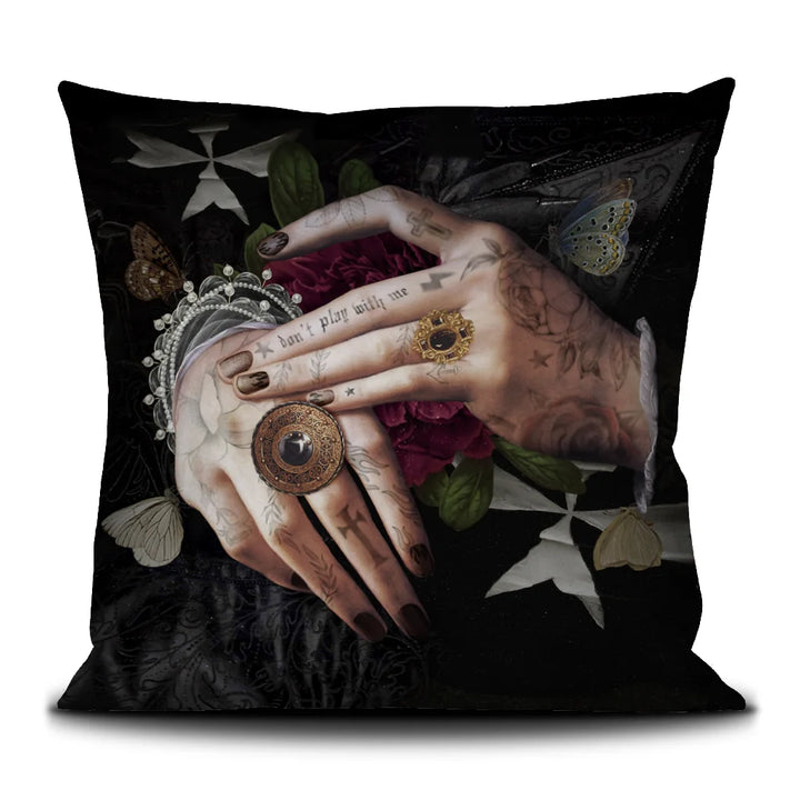 Kuvassa Voglio Bene -tyyny Protection -kuvituksella. Tatuoidut kädet lepäävät limittäin, sormissa tummia sormuksia ja käsien alla punainen kukka, taustana tumma goottinen kuviointi.
The Voglio Bene cushion with Protection illustration. Tattooed hands rest intertwined, adorned with dark rings, with a red flower beneath them against a dark gothic background.