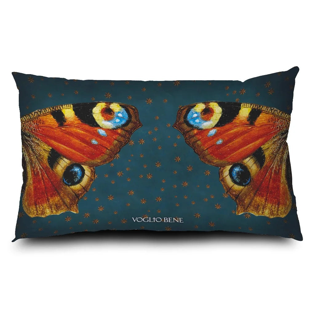 Kuvassa Voglio Bene -tyyny Sacred Butterfly -kuvituksella. Kuvan sivuissa perhosen siipi molemmillla puolilla. Taustalla sinisellä pohjalla näkyy tähtikuvioita.
The Voglio Bene cushion with Sacred Butterfly illustration. singular wings are shown on the sides of the picture. The blue background has starry ornaments.