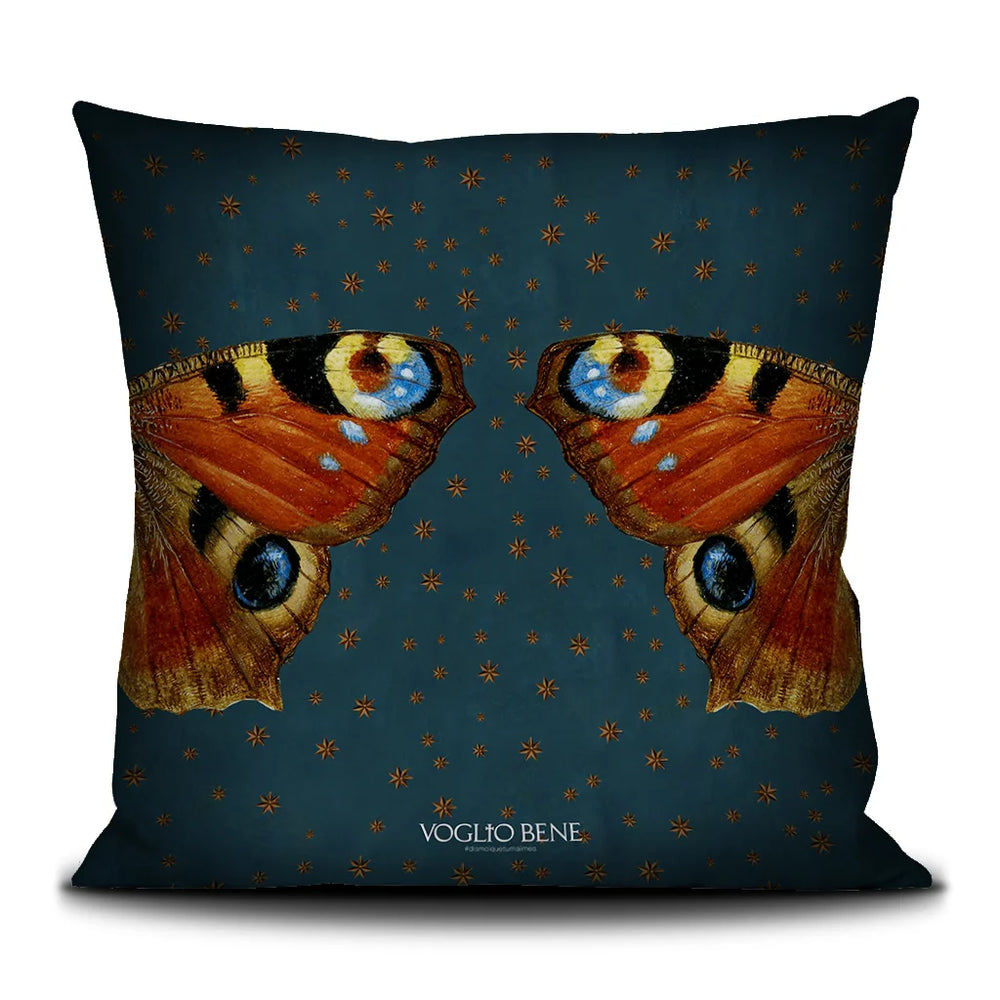 Kuvassa Voglio Bene -tyyny Sacred Butterfly -kuvituksella. Kuvan sivuissa yksin perhosen siipi molemmillla puolilla. Taustalla sinisellä pohjalla näkyy tähtikuvioita.
The Voglio Bene cushion with Sacred Butterfly illustration. Two singular wings are shown on the sides of the picture. The blue background has starry ornaments.