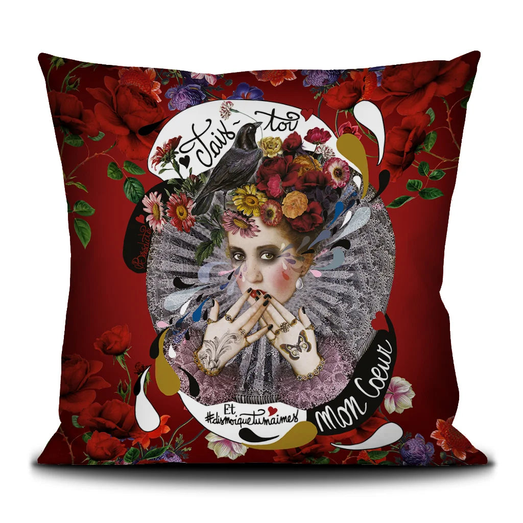 Kuvassa Voglio Bene tyynyn etupuoli Shut Up -kuvituksella, jossa harlekiinimäinen nainen peittää suunsa käsillään, päässään kukkaseppele ja ympärillään kukkia punaisella taustalla.
In the image, the front side of a Voglio Bene cushion with the Shut Up illustration, featuring a harlequin-like woman covering her mouth with her hands, wearing a flower crown and surrounded by flowers on a red background.