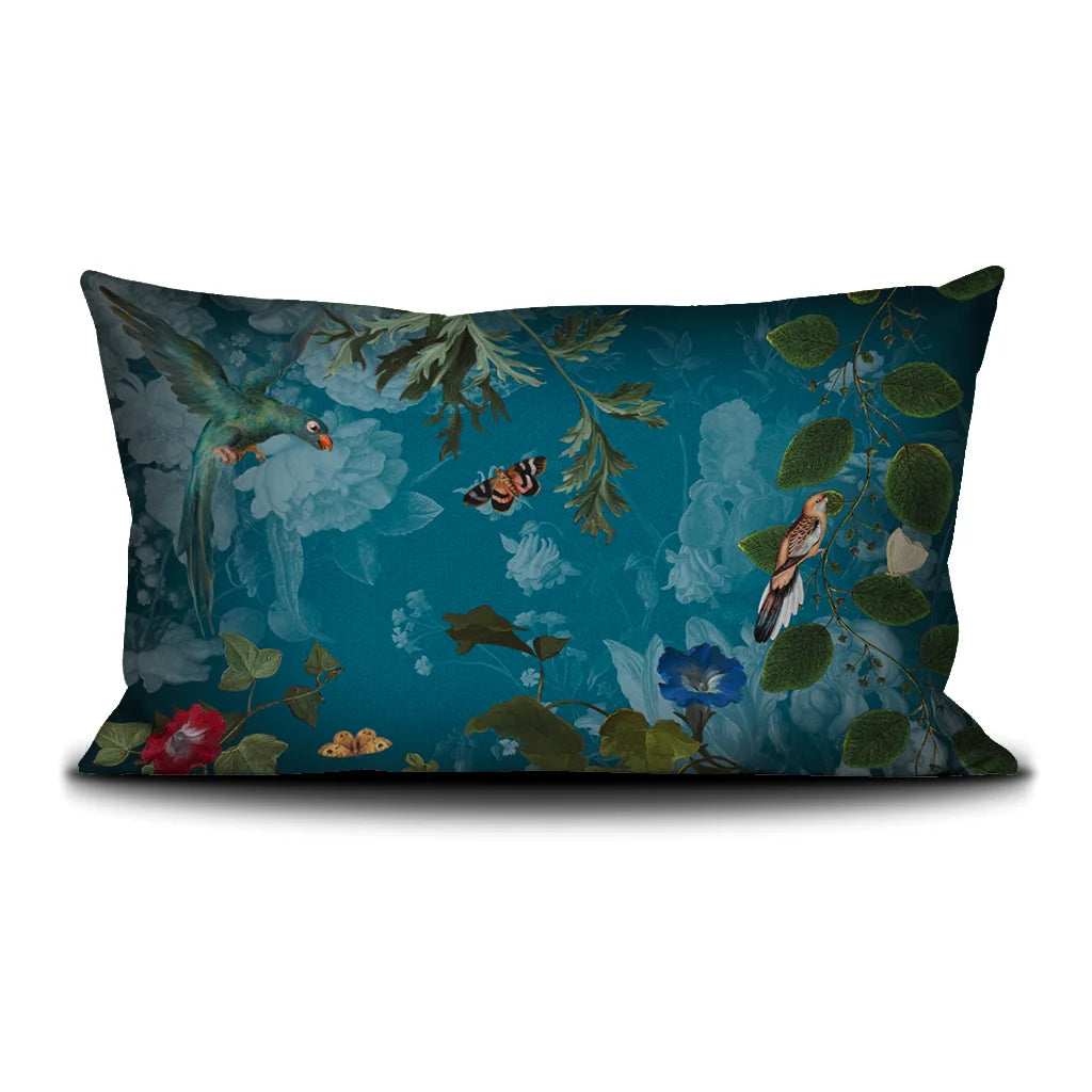 Kuvassa Voglio Bene -tyynyn takapuoli Tree of Life -kuvituksella. Papukaija ja perhonen lentävät kasvien koristamalla sinisellä taustalla.
The back of the Voglio Bene cushion with the Tree of Life illustration. A parrot and a butterfly flying against a blue background decorated with plants.