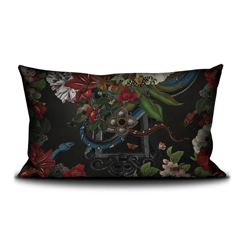 Kuvassa Voglio Bene tyynyn takapuoli Turmoil -kuvituksella, jossa tumma peili on kukkien ja käärmeiden ympäröimänä.
In the image, the back side of a Voglio Bene cushion with the Turmoil illustration, showing a dark mirror framed by flowers and snakes.
