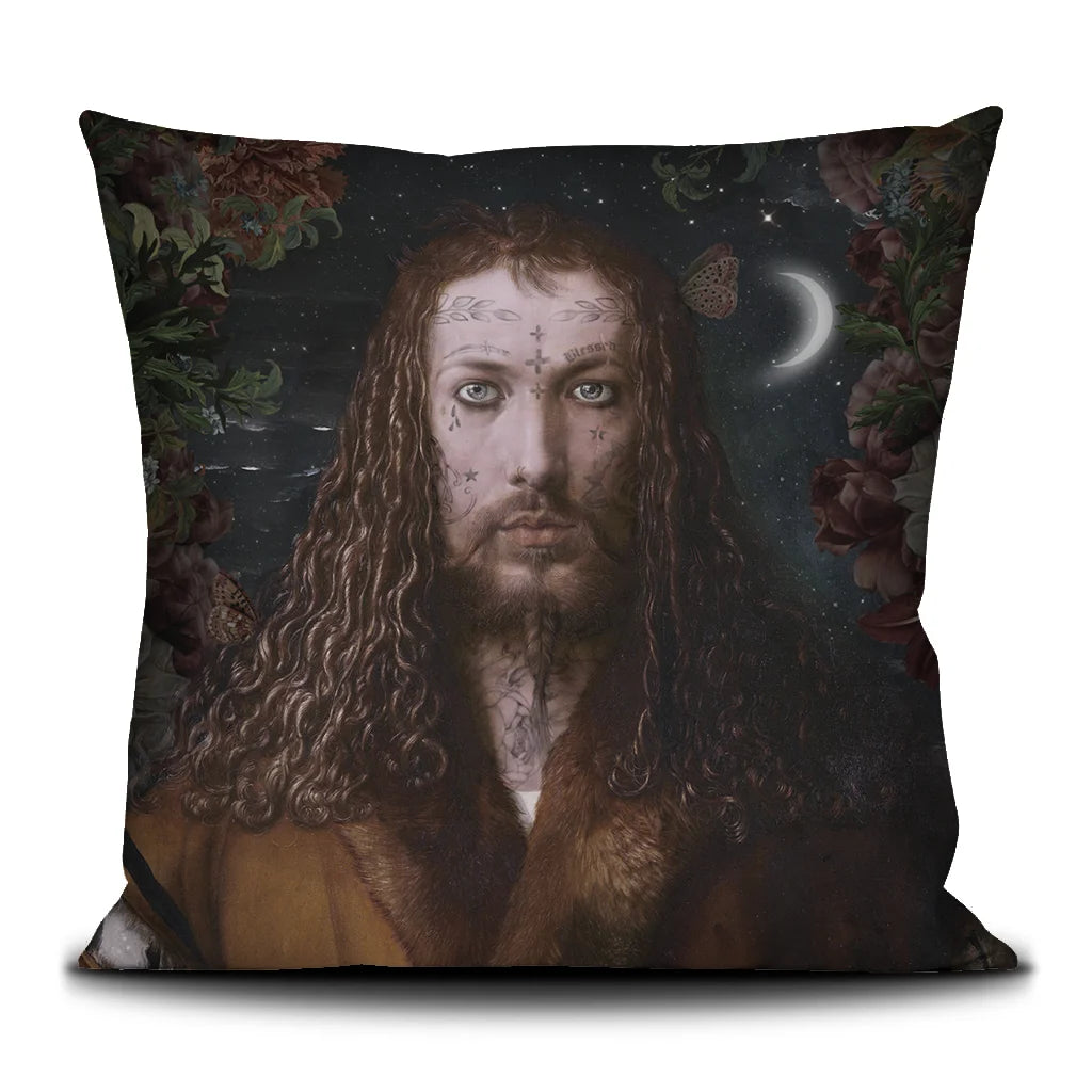 Kuvassa Voglio Bene -tyyny The Viking -kuvituksella. Tatuoitu Jeesusta muistuttava mies seisoo yötaivaan ja kuutamon edessä kukkien reunustamana.
The Voglio Bene cushion with The Viking illustration. A tattooed man resembling Jesus stands beneath the moonlit night sky surrounded by flowers.