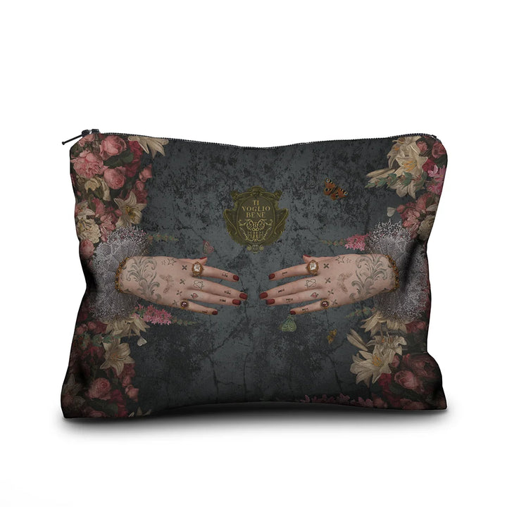 Voglio Bene Poderosa -samettipussukan etunäkymä, koko 17 × 23 cm. Kuvassa kaksi tatuoitua, sormuksilla koristeltua kättä osoittavat toisiaan kukkien reunustamana.
Front view of a Voglio Bene Poderosa velvet pouch, size 17 × 23 cm. The illustration shows two tattooed hands adorned with rings, pointing toward each other, framed by flowers.