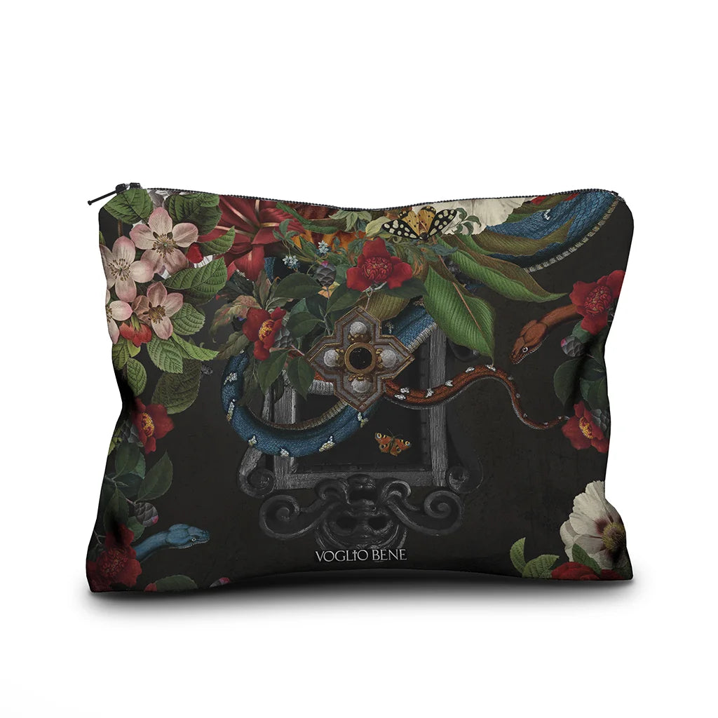 Kuvassa Voglio Bene samettipussukan takapuoli Turmoil -kuvituksella, jossa tumma peili on kukkien ja käärmeiden ympäröimänä.
In the image, the back side of a Voglio Bene velvet pouch with the Turmoil illustration, showing a dark mirror framed by flowers and snakes.