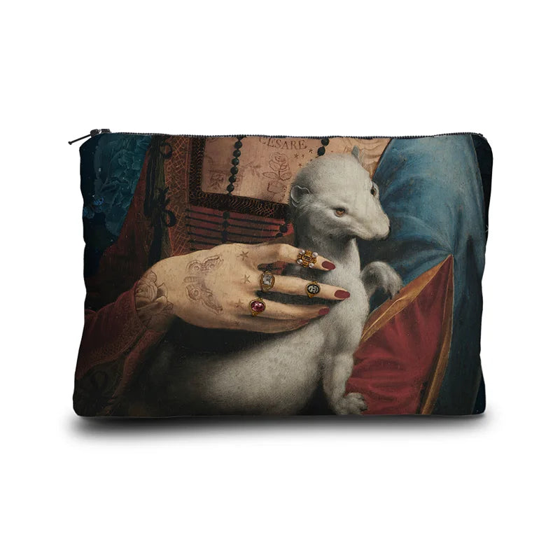 Kuvassa Voglio Bene -kukkaron takapuoli Cecilia-kuvituksella. Tatuoidun naisen rintakehä, jossa hän pitelee valkoista minkkiä.
The back of the Voglio Bene coin purse with the Cecilia illustration. The chest of a tattooed woman holding a white mink.