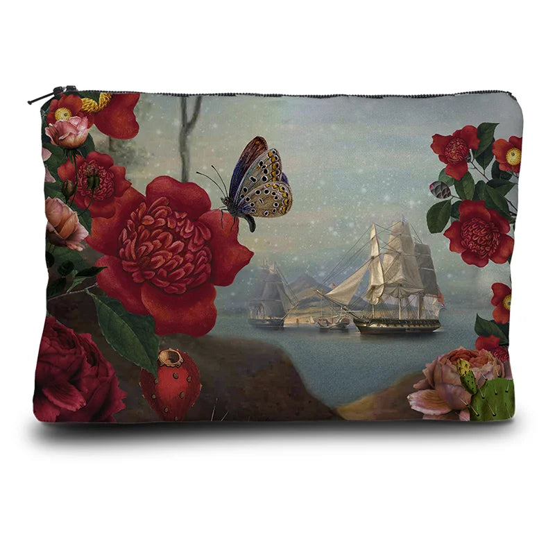 Kuvassa Voglio Bene kukkaron takapuoli Santa di U Niolu -kuvituksella, jossa näkyy lisää laivoja kukkien ja perhosen reunustamana.
In the image, the back side of a Voglio Bene purse with the Santa di U Niolu illustration, showing more ships framed by flowers and a butterfly.