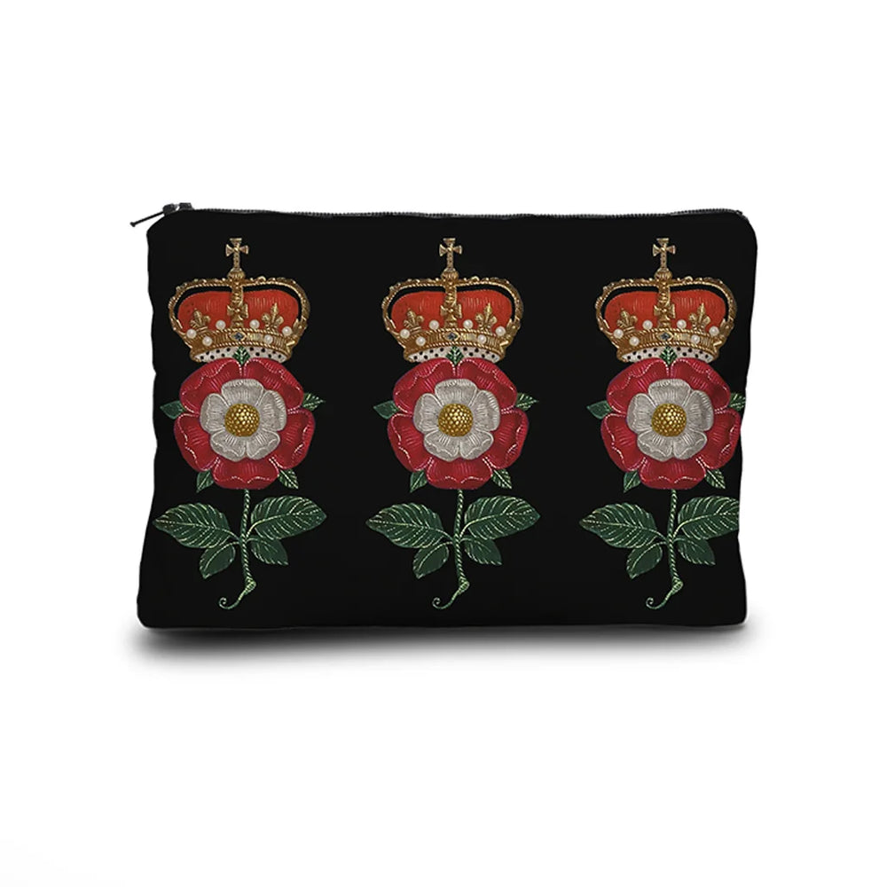 Kuvassa Voglio Bene -kukkaro Notre Dame -kuvituksella. Kolme kertaa punavalkoinen kukka, jonka päällä on kruunu, erottuu tummalla geometrisella taustalla.
The Voglio Bene purse with Notre Dame illustration. Three times a red and white flower crowned with a golden crown stands out against a dark geometric background.