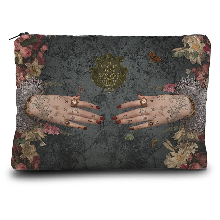 Voglio Bene Poderosa -kukkaron takanäkymä. Kuvassa kaksi tatuoitua, sormuksilla koristeltua kättä osoittavat toisiaan kukkien reunustamana.
Back view of a Voglio Bene Poderosa purse. The illustration shows two tattooed hands adorned with rings, pointing toward each other, framed by flowers.