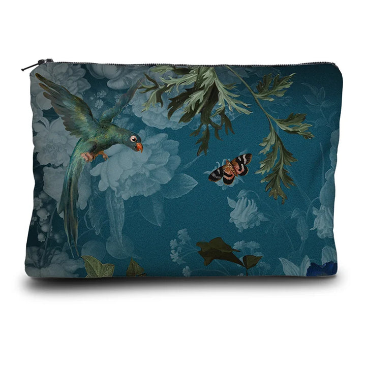 Kuvassa Voglio Bene -kukkaron takapuoli Tree of Life -kuvituksella. Papukaija ja perhonen lentävät kasvien koristamalla sinisellä taustalla.
The back of the Voglio Bene purse with the Tree of Life illustration. A parrot and a butterfly flying against a blue background decorated with plants.