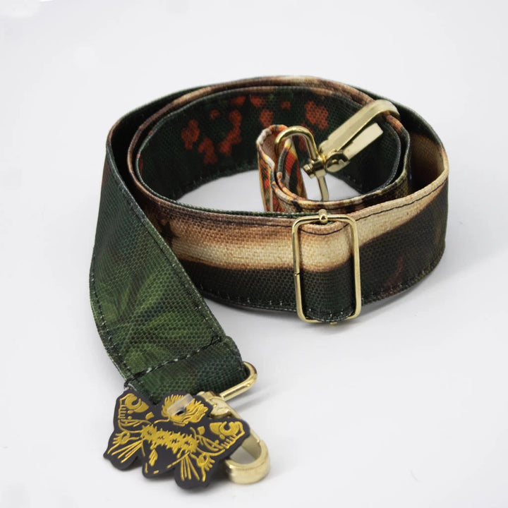 Kuvassa vihreä Voglio Bene -olkahihna La Vida -kuvituksella. Hihnassa on värikkäitä kukkia ja tyylitelty luurangon sivuprofiili koristeellisena elementtinä.
Illustration of a green Voglio Bene shoulder strap with the La Vida artwork. The strap features colorful flowers and a stylized side profile of a skeleton.