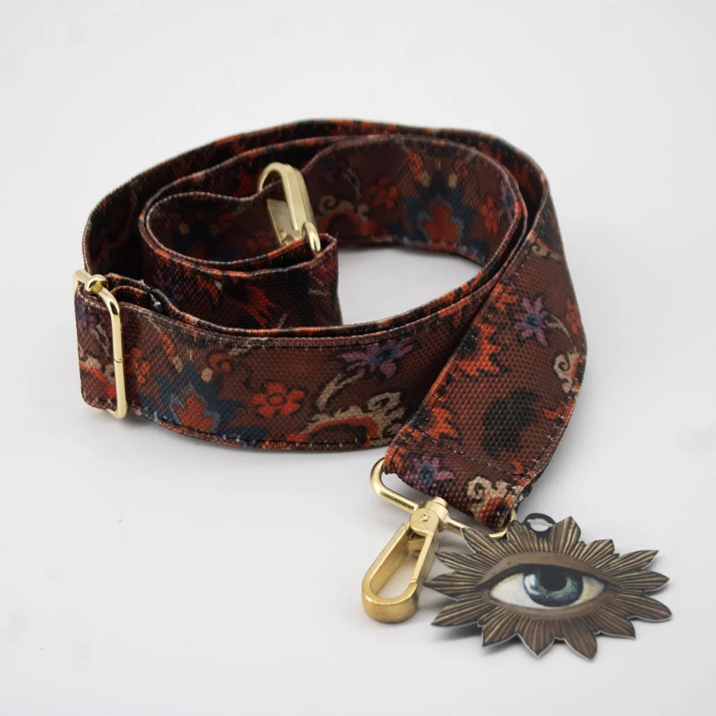 Kuvassa Voglio Bene -olkahihna oriental-kuvituksella. Punaisessa olkahihnassa on koristeellisia kukkia ja ornamenttimaisia yksityiskohtia.
Illustration of a Voglio Bene shoulder strap with an oriental motif. The red strap features decorative flowers and ornamental details.