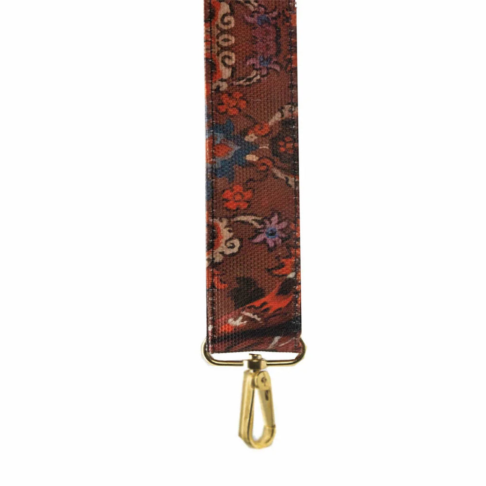 Kuvassa Voglio Bene -olkahihna oriental-kuvituksella. Punaisessa olkahihnassa on koristeellisia kukkia ja ornamenttimaisia yksityiskohtia.
Illustration of a Voglio Bene shoulder strap with an oriental motif. The red strap features decorative flowers and ornamental details.