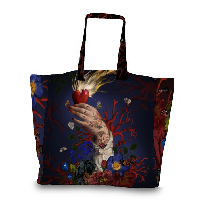 Kuvassa Voglio Bene tote bagin takapuoli Amen -kuvituksella. Käsi pitää palavaa sydäntä sinisellä taustalla, sormissa on tatuoitu Amen ja kättä ympäröivät korallit ja perhoset.
The back of the Voglio Bene tote bag with Amen illustration. A hand holds a flaming heart against a blue background, with Amen tattooed on the fingers, surrounded by corals and butterflies.