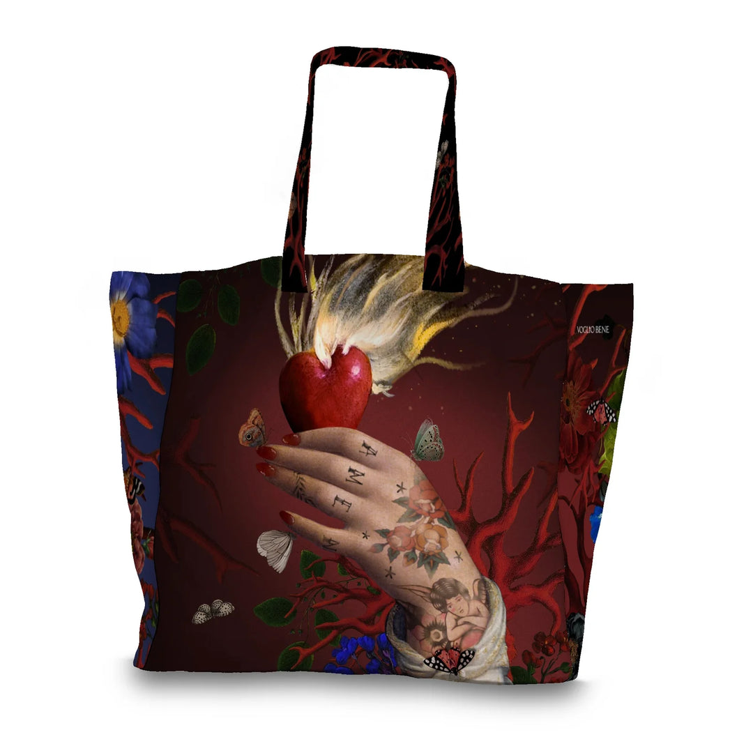 Kuvassa Voglio Bene tote bag Amen -kuvituksella. Käsi pitää palavaa sydäntä punaisella taustalla, sormissa on tatuoitu Amen ja kättä ympäröivät korallit ja perhoset.
The Voglio Bene tote bag with Amen illustration. A hand holds a flaming heart against a red background, with Amen tattooed on the fingers, surrounded by corals and butterflies.