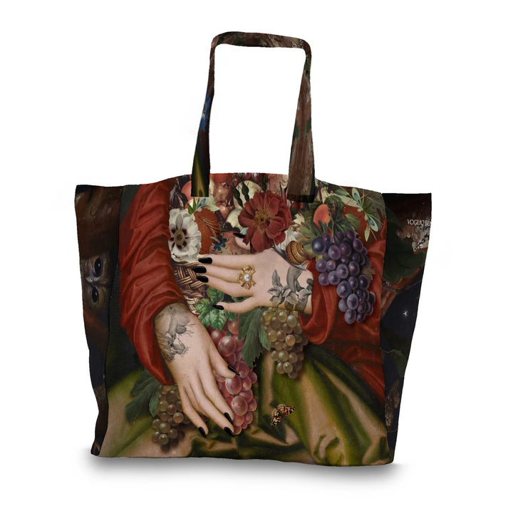 Kuvassa Voglio Bene tote bagin takapuoli Autumn-kuvituksella. Tatuoidut kädet pitelevät runsasta kukista ja hedelmistä koostuvaa asetelmaa.
The back of the Voglio Bene tote bag with Autumn illustration. Tattooed hands hold a rich arrangement of flowers and fruits.