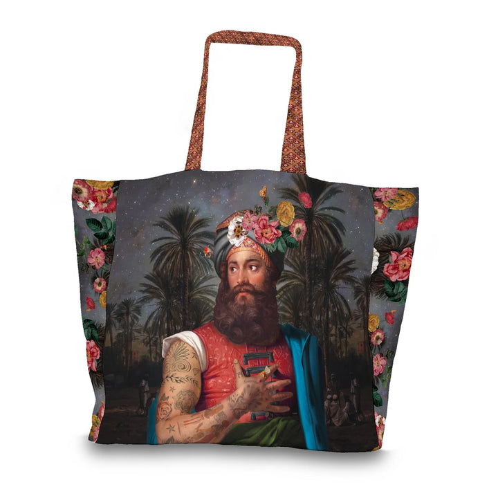 Voglio Bene The Great Belzoni -tote bag etunäkymä, jossa tatuoitu arabialainen mies on kuvattu yömaisemassa palmujen ja tähtitaivaan reunustamana.
Front view of a Voglio Bene The Great Belzoni tote bag, showing a tattooed Arab man in a night scene framed by palm trees and a starry sky.