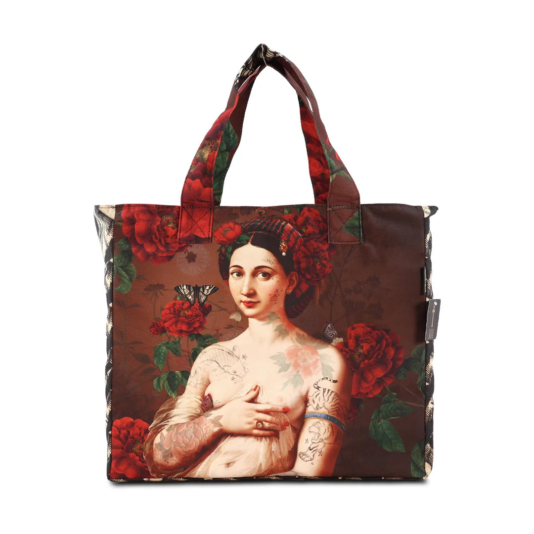 Kuvassa Voglio Bene -tote bag Fornarina -kuvituksella. Tatuoitu nainen kukkia hiuksissaan ruskealla taustalla, ympärillään kukkia ja perhosia.
The Voglio Bene tote bag with Fornarina illustration. A tattooed woman with flowers in her hair against a brown background, surrounded by flowers and butterflies.