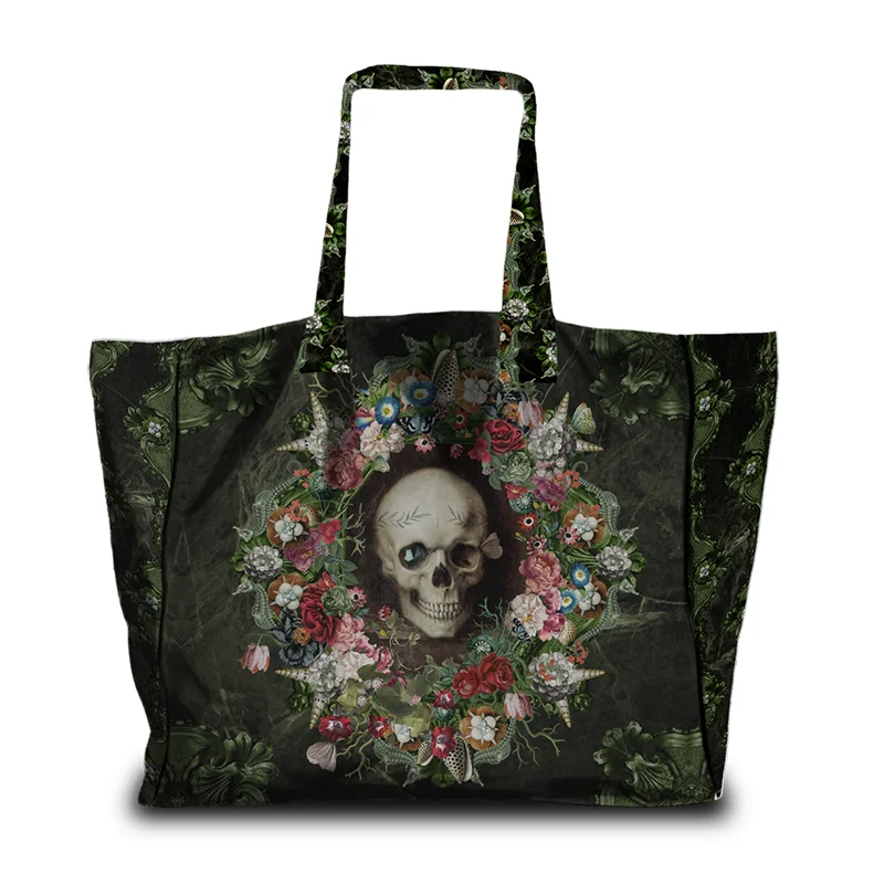 Voglio Bene The Froth of the Days -tote bag etunäkymä, jossa pääkalloa koristavat kukat ja simpukat yksityiskohtaisessa kuvituksessa.
Front view of a Voglio Bene The Froth of the Days tote bag, showing a skull adorned with flowers and seashells in detailed artwork.