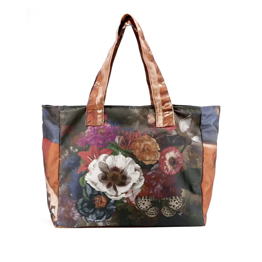 Kuvassa Voglio Bene tote bag takapuoli Hassan -kuvituksella, jossa kukkien päällä lepää valkoinen perhonen.
In the image, the back side of a Voglio Bene tote bag with the Hassan illustration, showing a white butterfly resting on flowers.