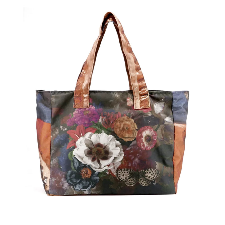 Kuvassa Voglio Bene tote bag takapuoli Hassan -kuvituksella, jossa kukkien päällä lepää valkoinen perhonen.
In the image, the back side of a Voglio Bene tote bag with the Hassan illustration, showing a white butterfly resting on flowers.