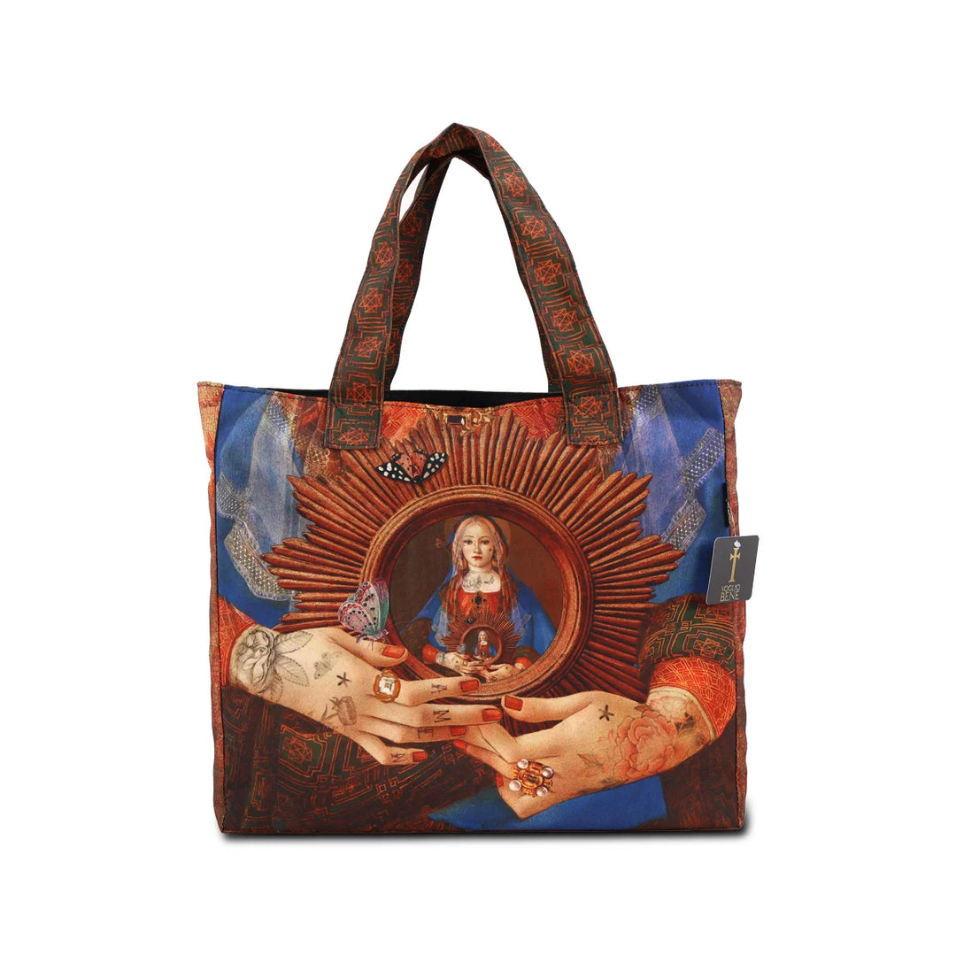 Kuvassa Voglio Bene -tote bag takapuoli Madonna Suprema -kuvituksella. Lähikuva naisen käsistä, jotka pitävät aurinkoa, jonka keskellä huntuun pukeutunut nainen toistuu.
The back of the Voglio Bene tote bag with Madonna Suprema illustration. Close-up of the woman’s hands holding a sun, with the veiled woman depicted at its center.