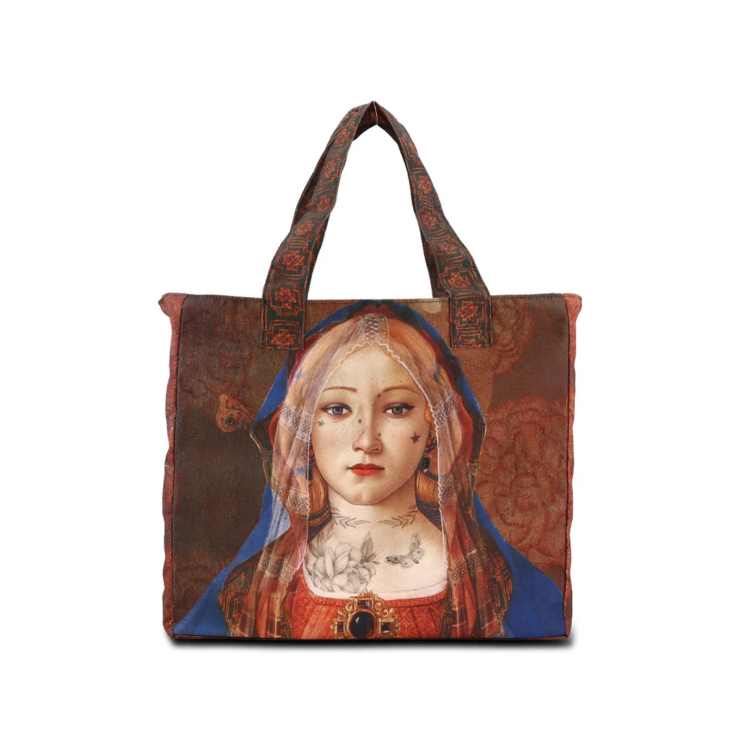 Kuvassa Voglio Bene -tote bag Madonna Suprema -kuvituksella. Tatuoitu huntuun pukeutunut nainen ruskealla taustalla.
The Voglio Bene tote bag with Madonna Suprema illustration. A tattooed woman wearing a veil against a brown background.