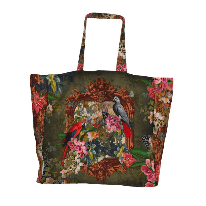 Voglio Bene Parrot -tote bag etunäkymä. Kuvassa kaksi papukaijaa istuu kukkaornamentti-asetelmassa rehevän taustan edessä.
Front view of a Voglio Bene Parrot tote bag. The illustration shows two parrots perched within a floral ornamental arrangement against a lush backdrop.