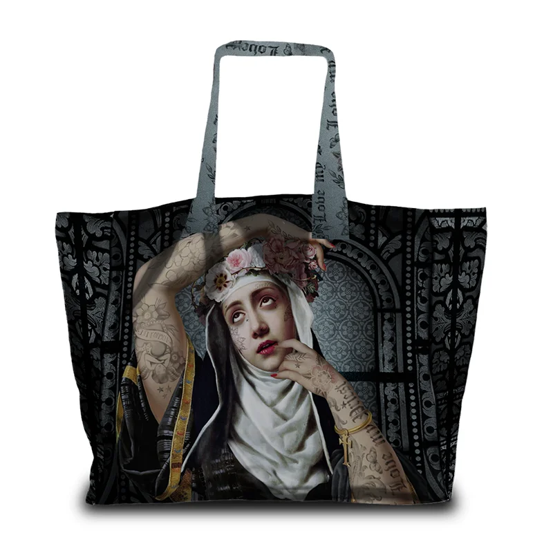 Kuvassa Voglio Bene tote bag etupuoli Saint Rita -kuvituksella, jossa tatuoitu nunna kukkaseppele päässä on kuvattuna tummalla ornamenttikuvioisella taustalla.
In the image, the front side of a Voglio Bene tote bag with the Saint Rita illustration, depicting a tattooed nun wearing a flower crown against a dark ornamental background.