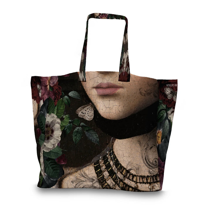 Kuvassa Voglio Bene tote bagin takapuoli Starfire-kuvituksella. Tatuoidun naisen kaula ja rintakehä tummalla taustalla perhosten ja kasvien reunustamana.
The back of the Voglio Bene tote bag with the Starfire illustration. The tattooed woman’s neck and chest on a dark background framed by butterflies and plants.