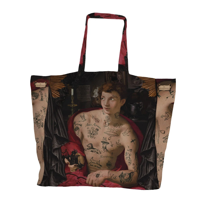 Voglio Bene Tattoo Artist’s Kit -tote bag takanäkymä, jossa tatuoitu tatuoija on kuvattu punaisessa viitassa.
Back view of a Voglio Bene Tattoo Artist’s Kit tote bag, featuring a tattooed tattoo artist wearing a red cloak.
