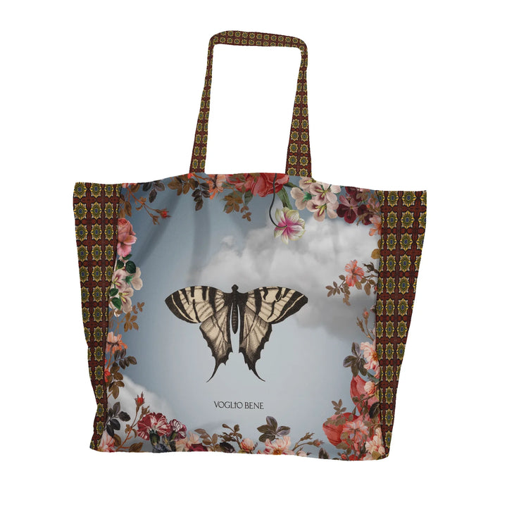 Kuvassa Voglio Bene tote bagin takapuoli The Spring -kuvituksella. Mustavalkoinen perhonen sinisellä taivaalla kukkien reunustamana.
The back of the Voglio Bene tote bag with The Spring illustration. A black and white butterfly against a blue sky framed by flowers.
