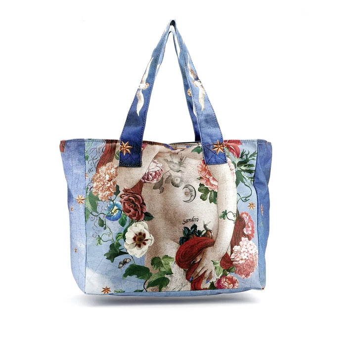 Kuvassa Voglio Bene tote bagin takapuoli Venus Gypsy -kuvituksella. Tatuoidun Venuksen lantio kukalla peitettynä.
The back of the Voglio Bene tote bag with the Venus Gypsy illustration. The tattooed Venus’s hips covered with a flower.