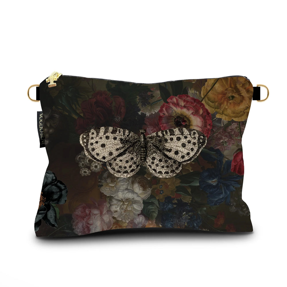 Kuvassa Voglio Bene samettilaukun takapuoli Hassan -kuvituksella, jossa kukkien päällä lepää valkoinen perhonen.
In the image, the back side of a Voglio Bene velvet bag with the Hassan illustration, showing a white butterfly resting on flowers.