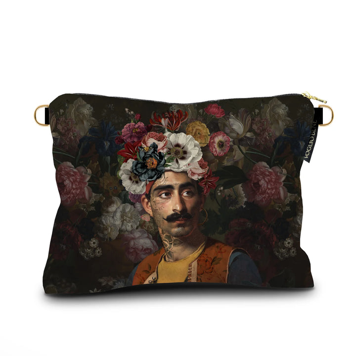 Kuvassa Voglio Bene samettilaukun etupuoli Hassan -kuvituksella, jossa viiksekäs tatuoitu mies kukkaturbaani päässä on kuvattuna tummanvihreällä taustalla, joka on täynnä kukkia.
In the image, the front side of a Voglio Bene velvet bag with the Hassan illustration, featuring a mustached tattooed man wearing a floral turban against a dark green flower-filled background.