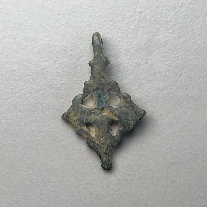 Viikinkiaikainen pronssinen ristiriipus, takapuoli, kulunut pinta ja ehjä ripustuslenkki - Viking Age bronze cross pendant, back view, worn surface with intact suspension loop.