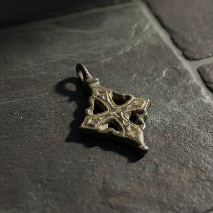 Viikinkiaikainen pronssinen ristiriipus, etupuoli, avoin kehyksellinen risti vihertävänruskealla patinalla - Viking Age bronze cross pendant, front view, openwork framed cross with greenish-brown patina.