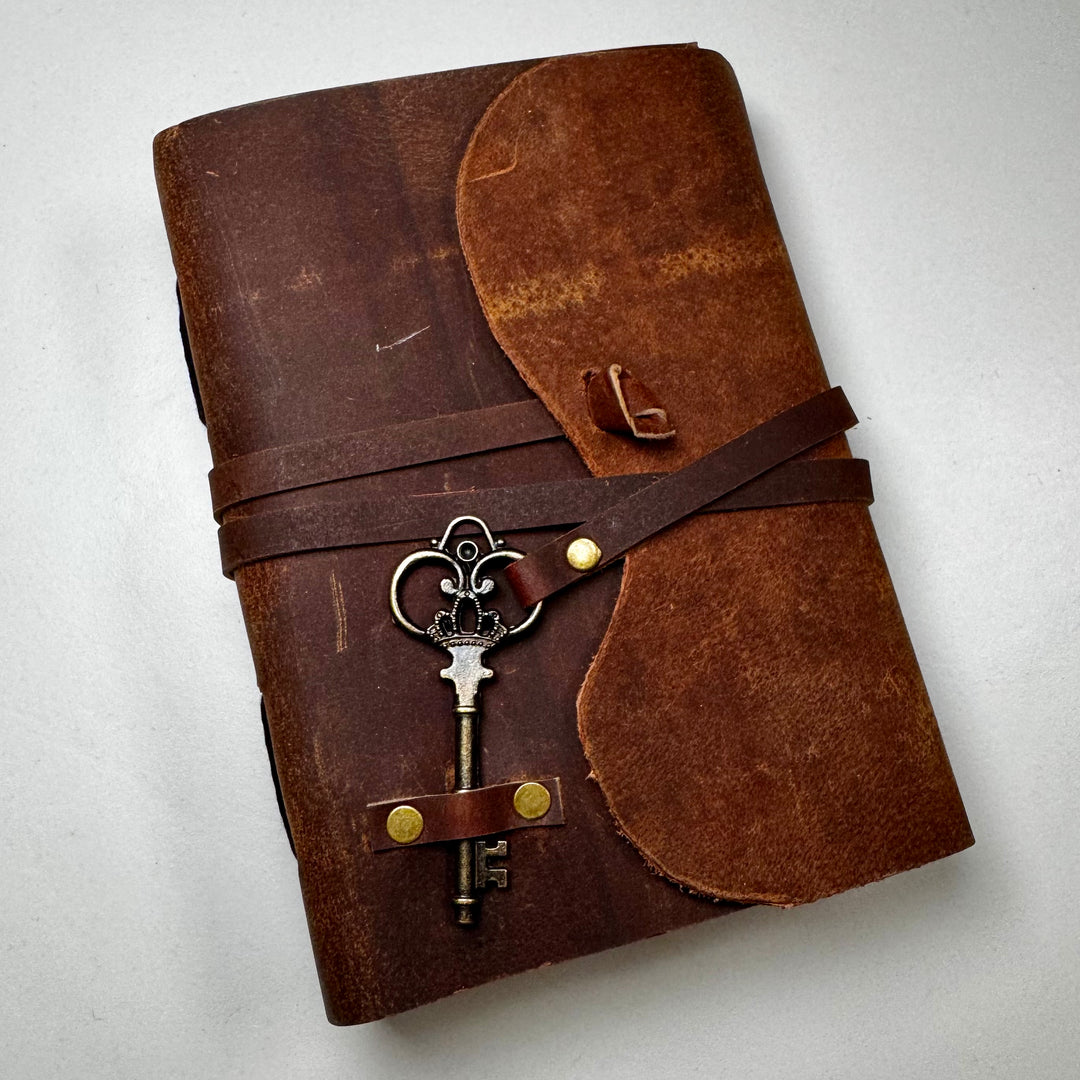 The Vintage Leather -muistikirjan nahkainen etukansi, jossa avain. - Front cover of The Vintage Leather notebook featuring key and decorative elements.