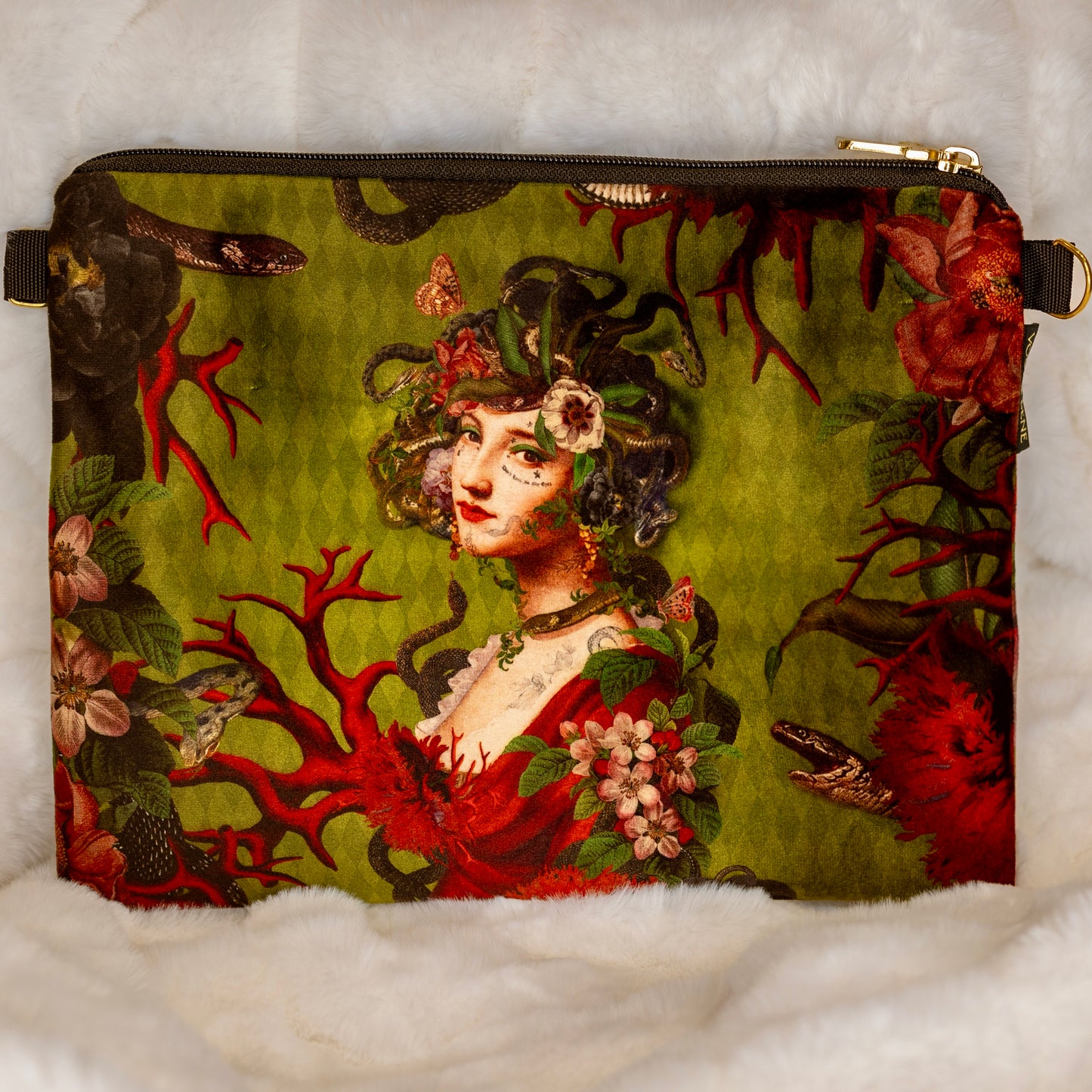 Kuva Voglio Benen ylellisestä samettipussukasta, jossa Meduusan rintakuvapainatus. Meduusan kasvot koristeltu kukilla ja lehdillä. -  Picture of a luxurious Voglio Bene velvet pouch with a Medusa bust print. Medusa's face is adorned with flowers and leaves, blending myth and beauty.