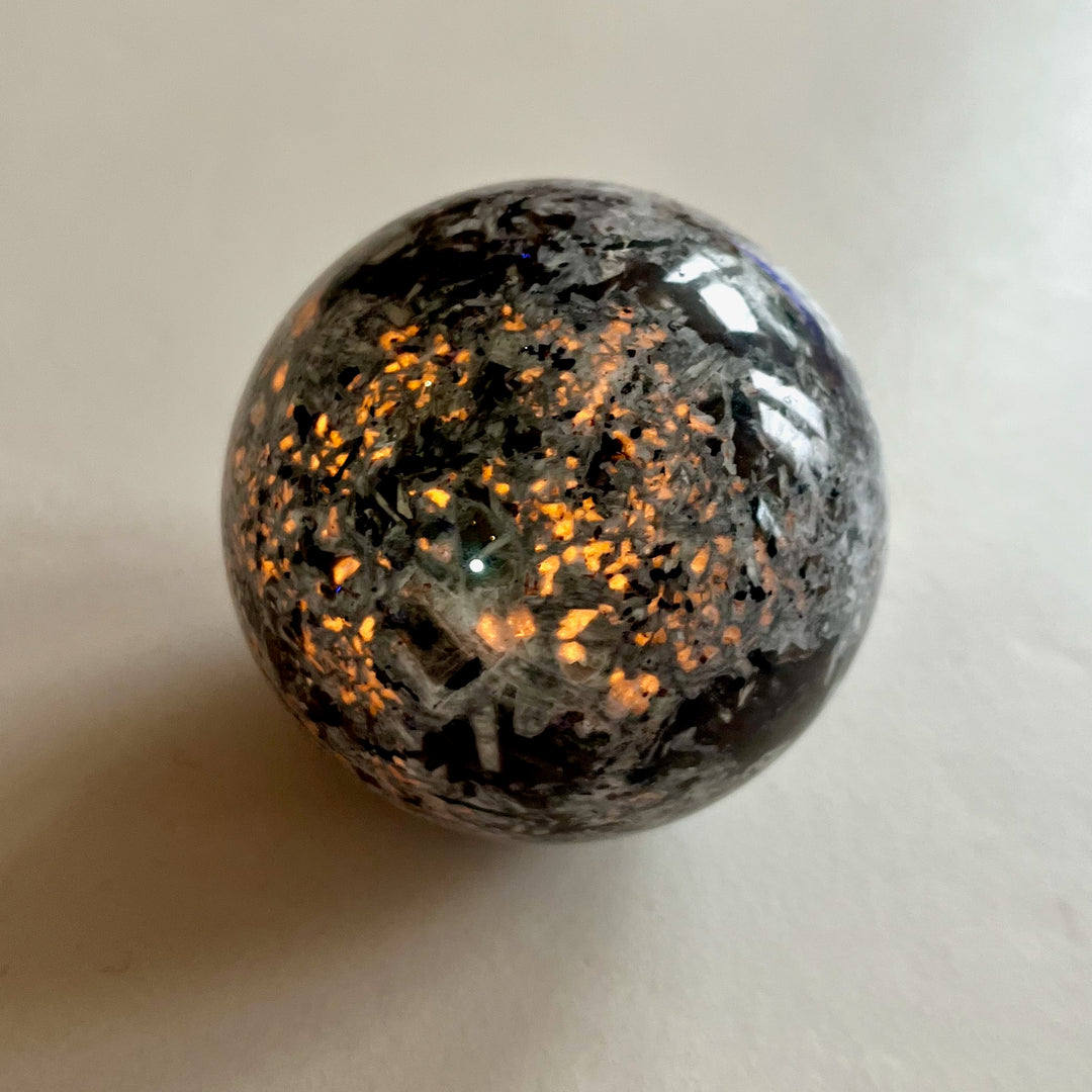Hehkuva Yooperlite-pallo, sodaliitti näkyvissä UV-valossa. -  Glowing Yooperlite sphere showing sodalite under UV light.