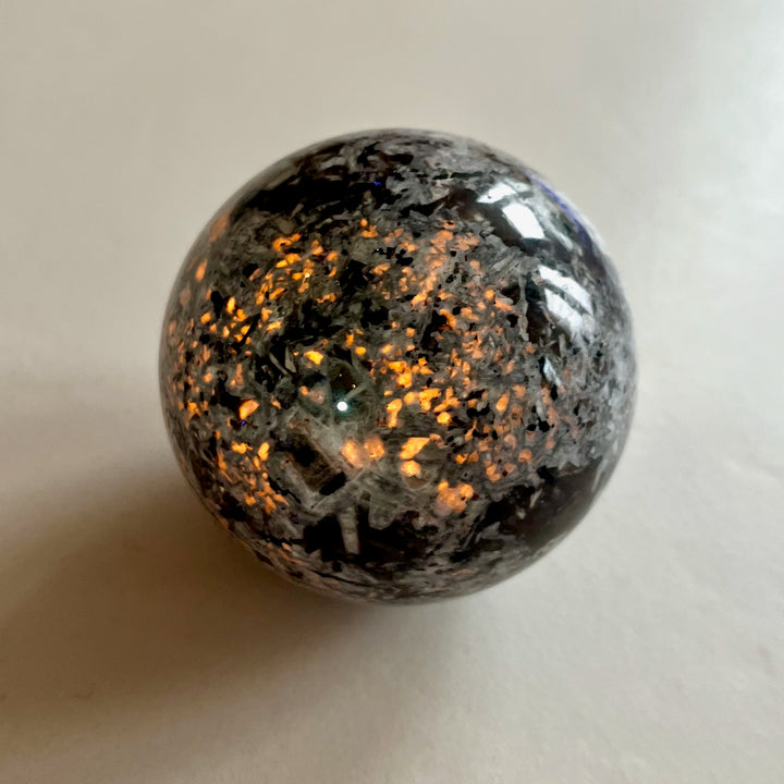 Hehkuva Yooperlite-pallo, sodaliitti näkyvissä UV-valossa. -  Glowing Yooperlite sphere showing sodalite under UV light.