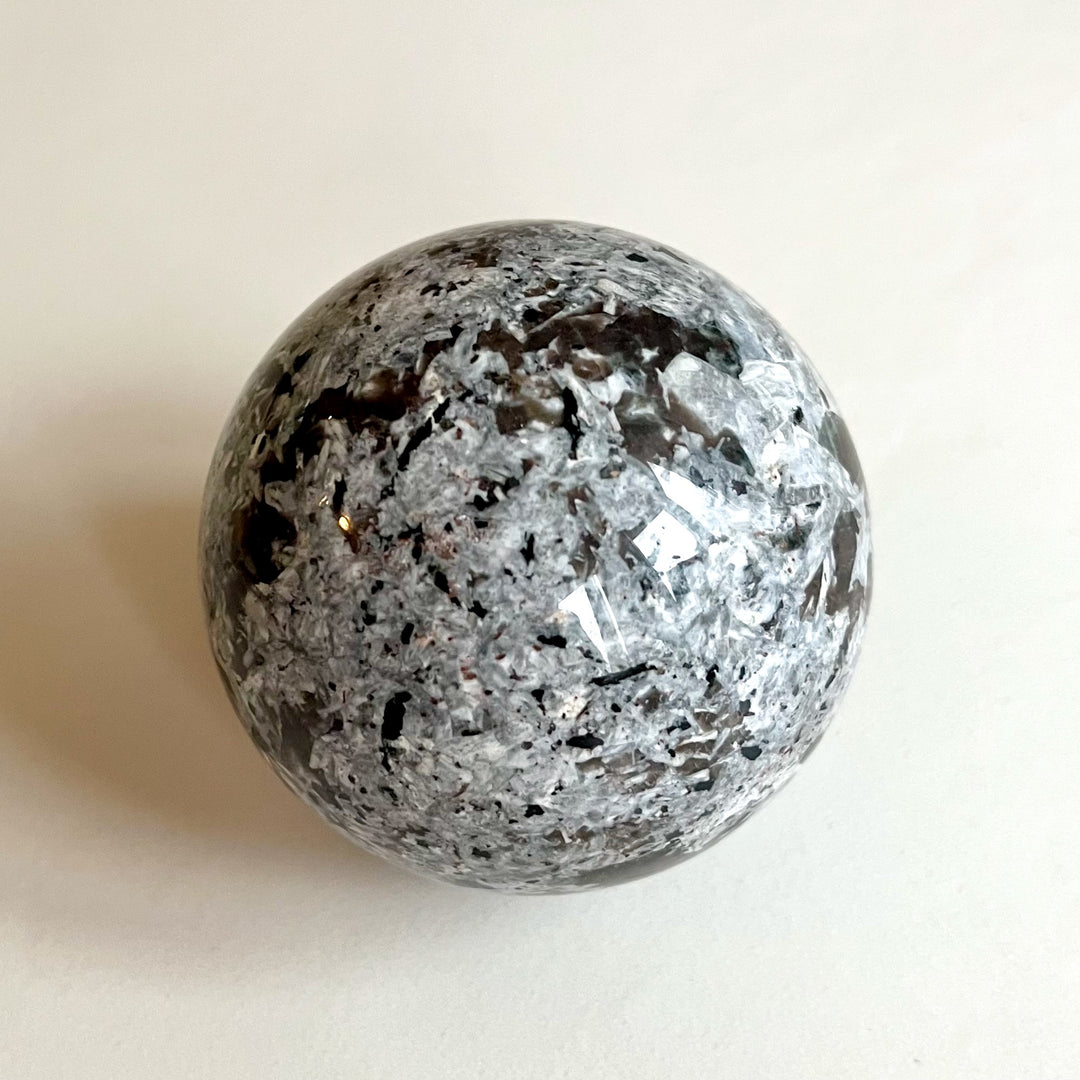 Yooperlite-pallo luonnonvalossa, harmaa ja rauhallinen. -  Yooperlite sphere in natural light, grey and neutral.