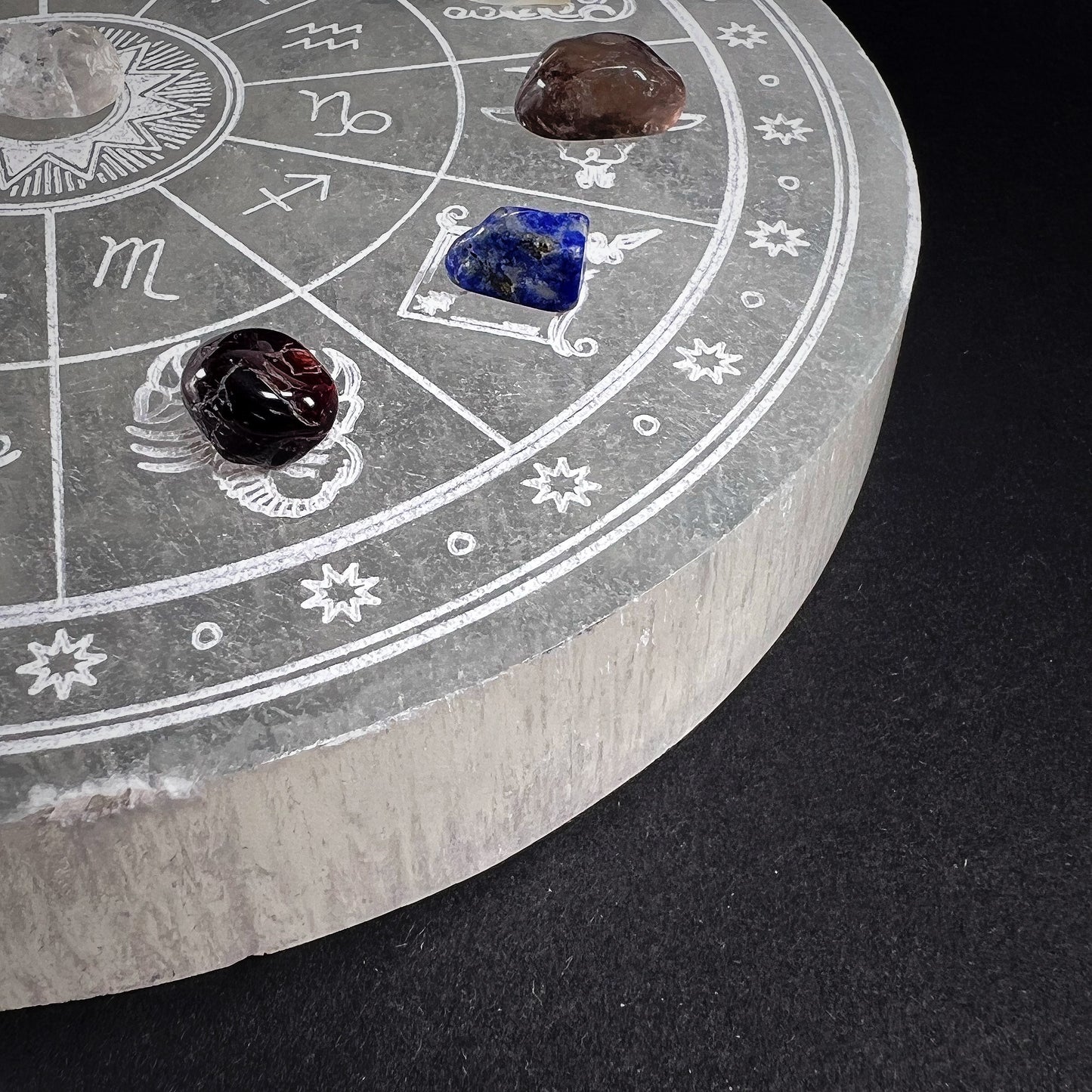 Round selenite plate with carved zodiac signs, added with different beautiful gem stones for each zodiac. Partial view of the product.