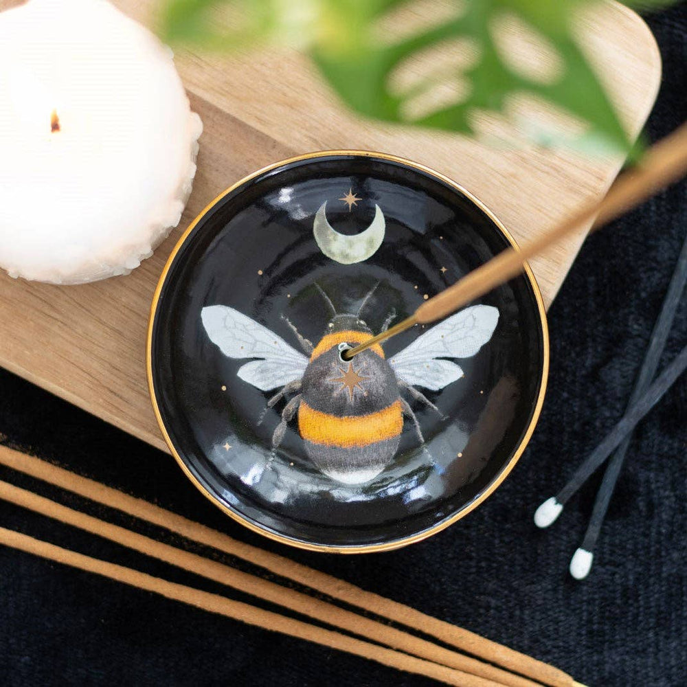 Musta Forest Bee -suitsukealusta suitsuketikun kanssa puualustalla, koristeena mehiläinen, kuunsirppi ja tähdet.