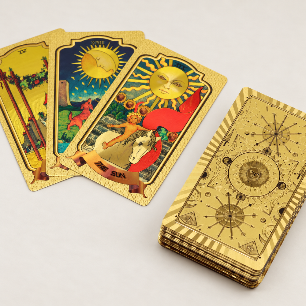Golden Rider-Waite Tarot -pakan Sauvojen nelonen, Kuu ja Aurinko sekä kullanvärinen, aurinko- ja tähtikuvioinen taustapuoli. / Four of Wands, The Moon and The Sun cards from Golden Rider-Waite Tarot, with the gold-coloured sun and star design on the card backs.