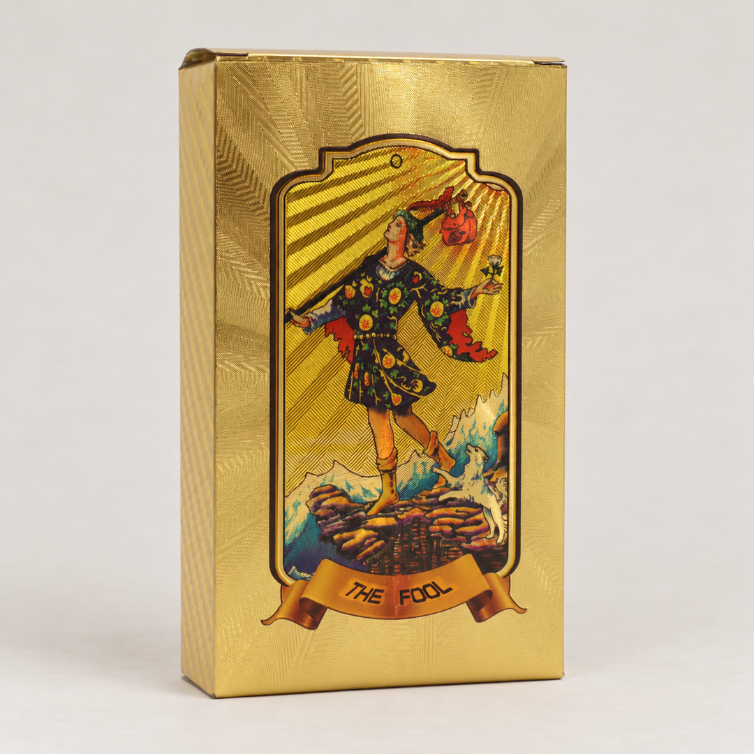 Golden Rider-Waite Tarot -korttipakan kullanvärinen kotelo, jonka kannessa on Narri-kortin kuvitus. / Gold-coloured Golden Rider-Waite Tarot box featuring The Fool on the front.