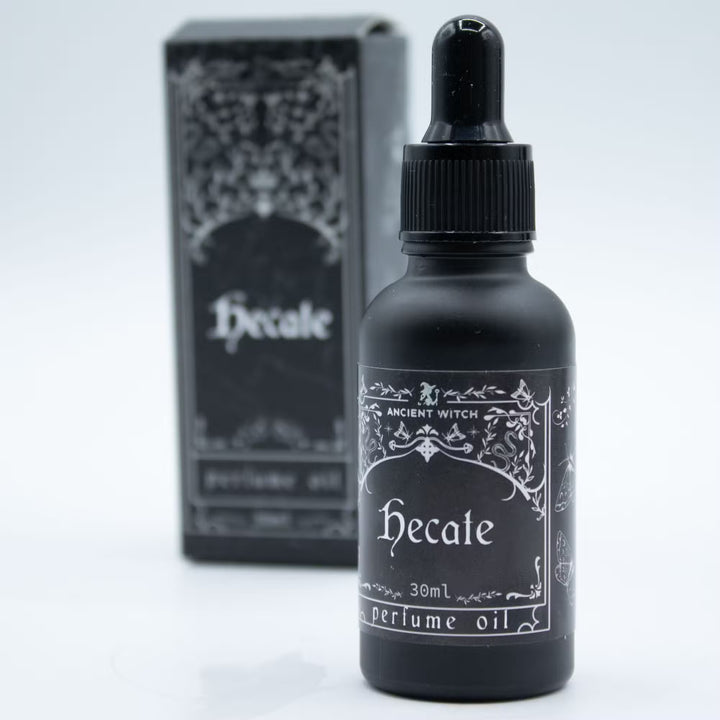 Hecate-parfyymiöljyn musta 30 ml pipettipullo lähikuvassa. / Close-up of the black 30 ml Hecate perfume oil dropper bottle.