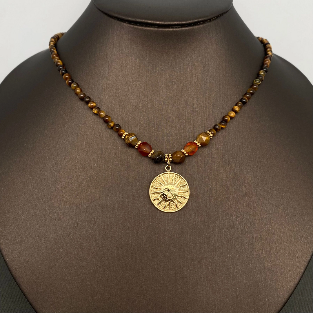 Front view of the Sun necklace on a dark jewellery display bust, with brown stone beads and a gold-coloured sun pendant.